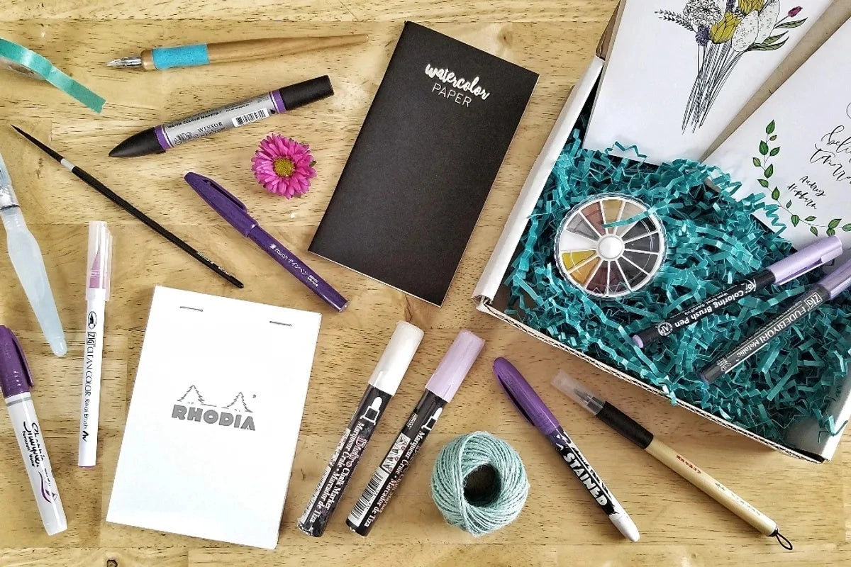 Overhead view of art supplies on table including markers and notebooks